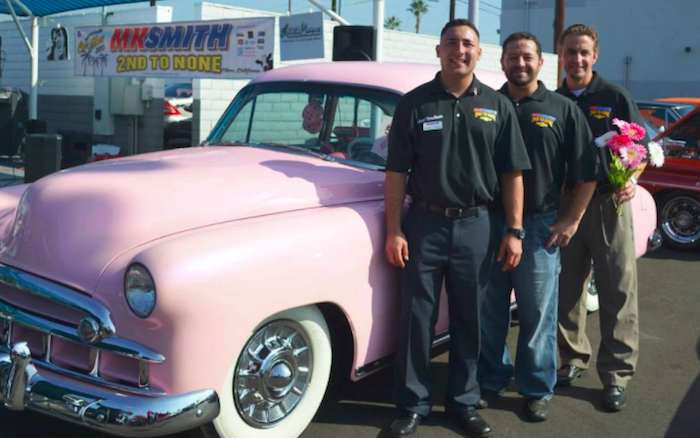 MK Smith Chevrolet employees next to a classic car